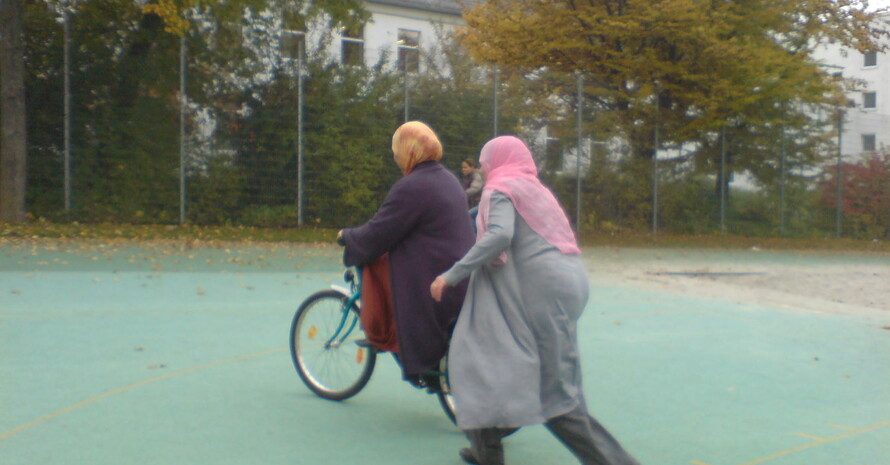 zwei Musliminnen helfen sich gegenseitig beim Fahrradkurs in Regensburg